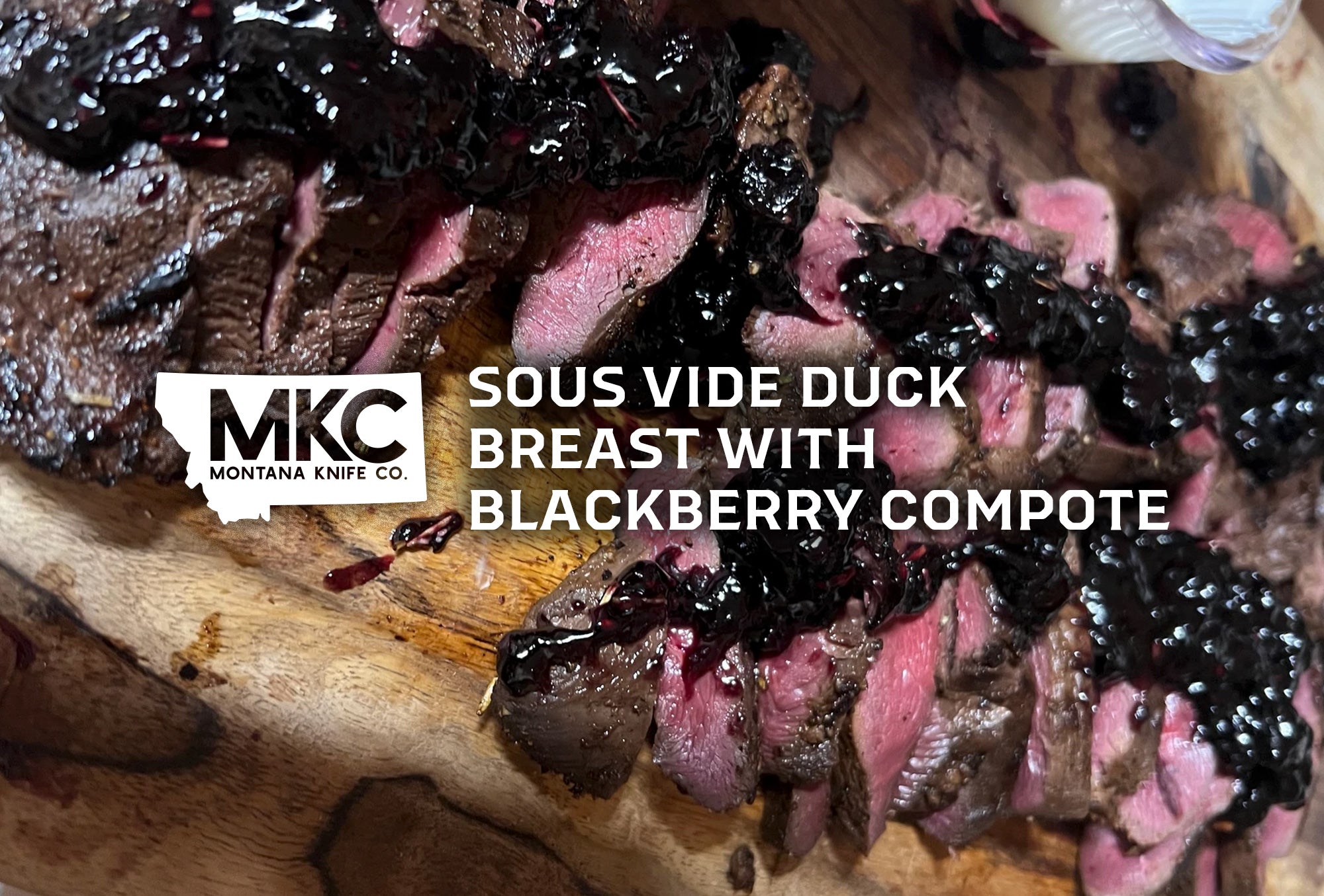 A sliced Sous Vide Duck Breast With Blackberry Compote rests on a wooden cutting board.