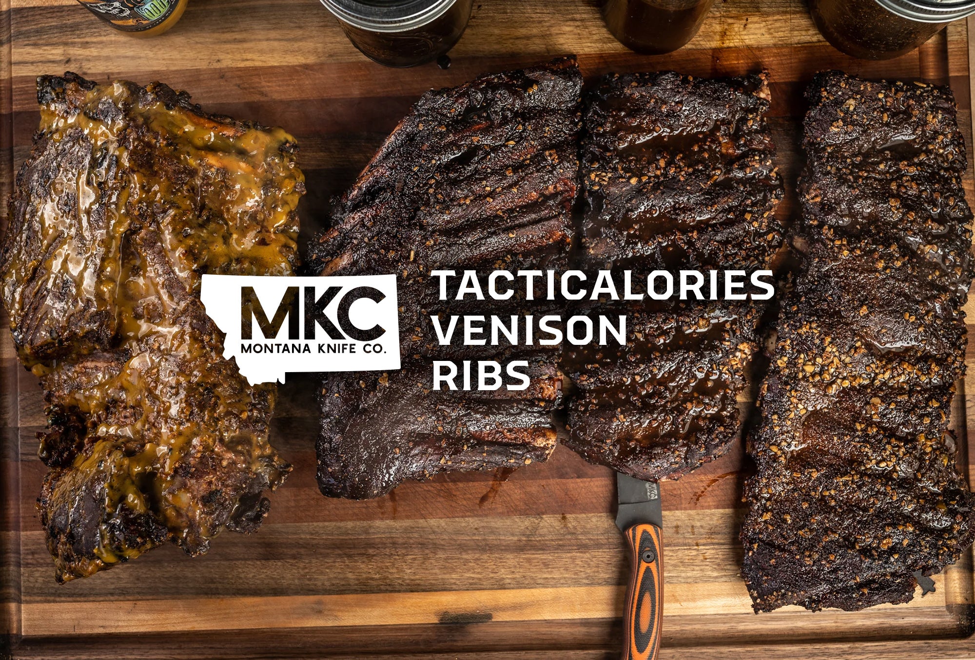 Venison ribs rest on a wood cutting board with an MKC knife resting on the edge.