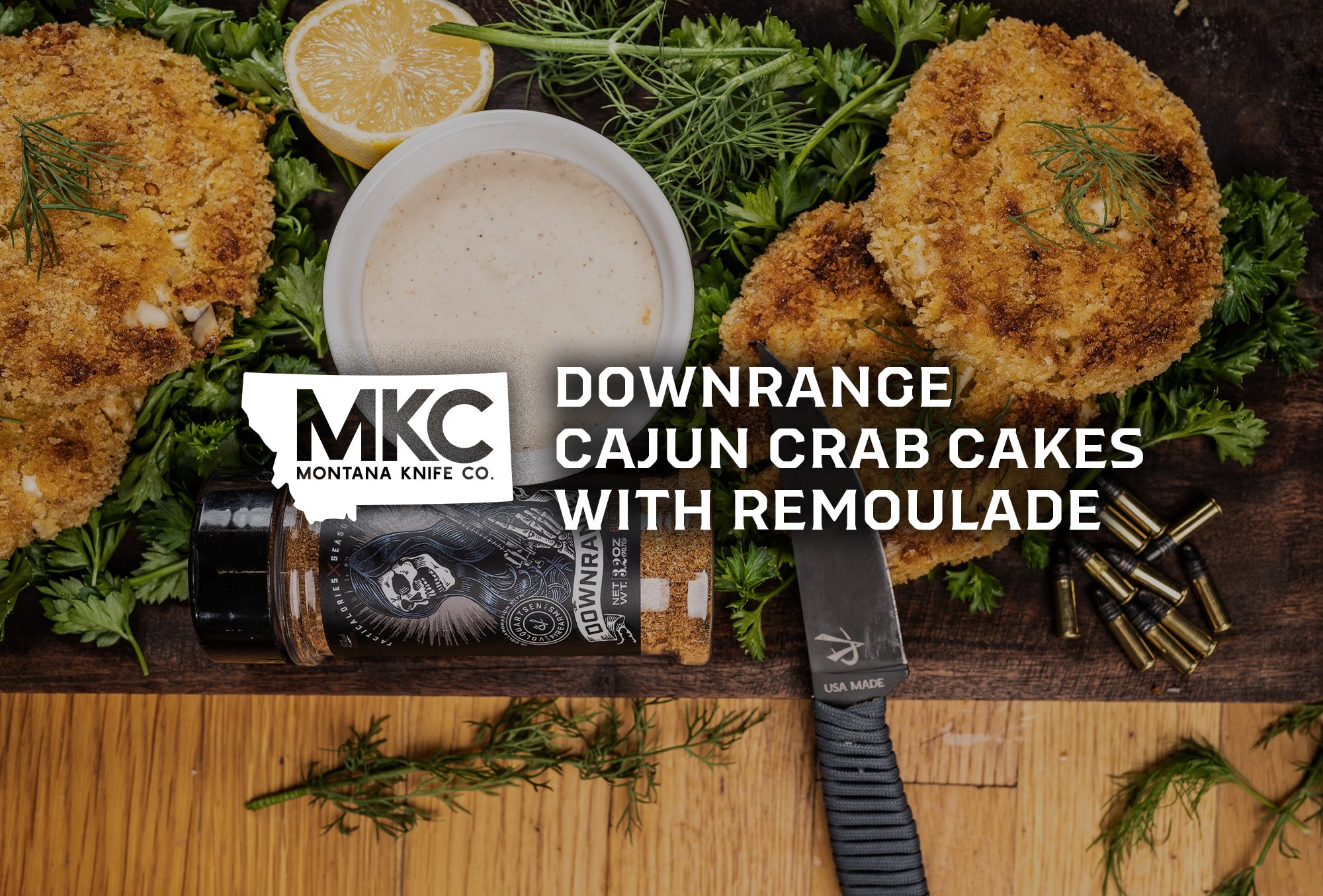 Golden-brown Cajun crab cakes with creamy remoulade, surrounded by fresh herbs, lemon, and a Montana Knife Company blade.