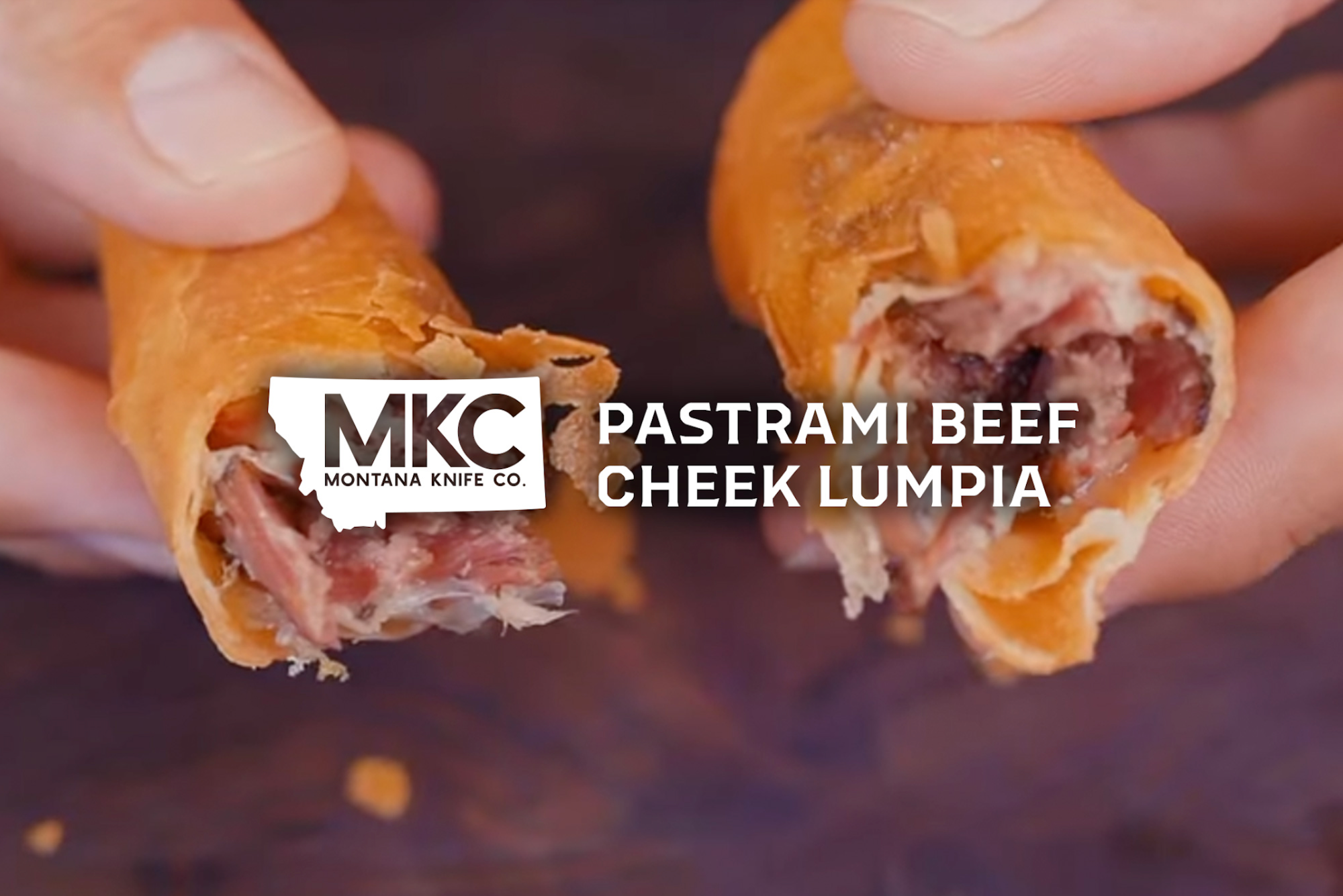 Beef cheek pastrami wrapped in a lumpia wrapper, held in two hands, showing the crispy exterior and filling.