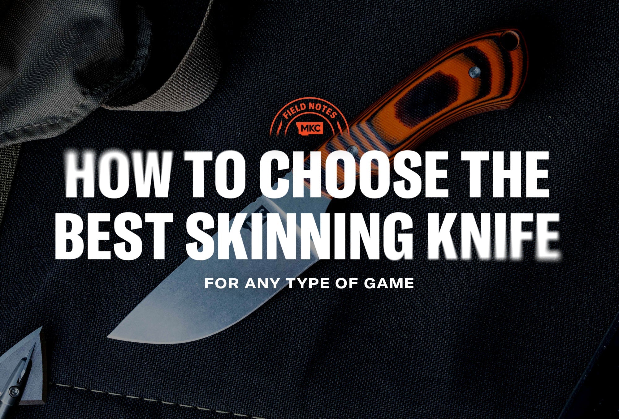 An MKC knife with an orange and black handle on a dark surface, presented as the best skinning knife.