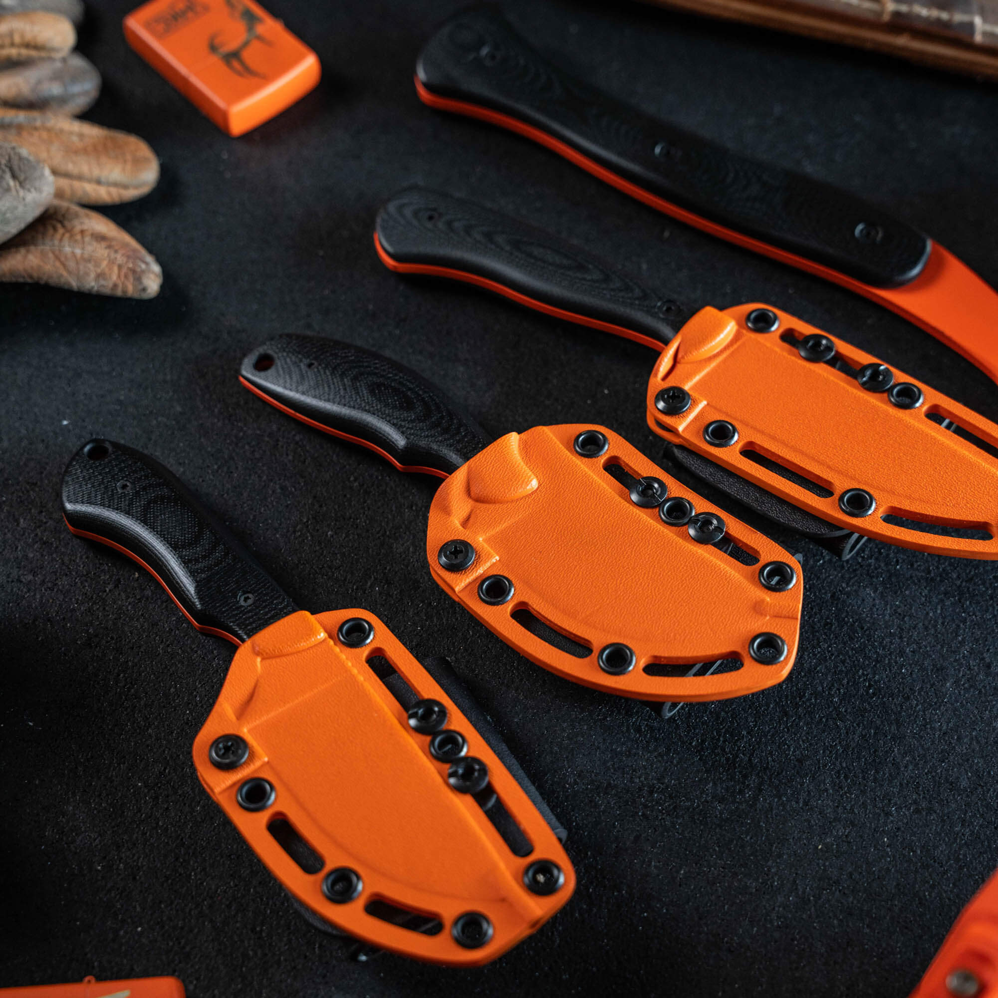 Full set of 8 Blaze Orange Cerakote knives with black handles, showcasing durable outdoor tools for hunting and work.