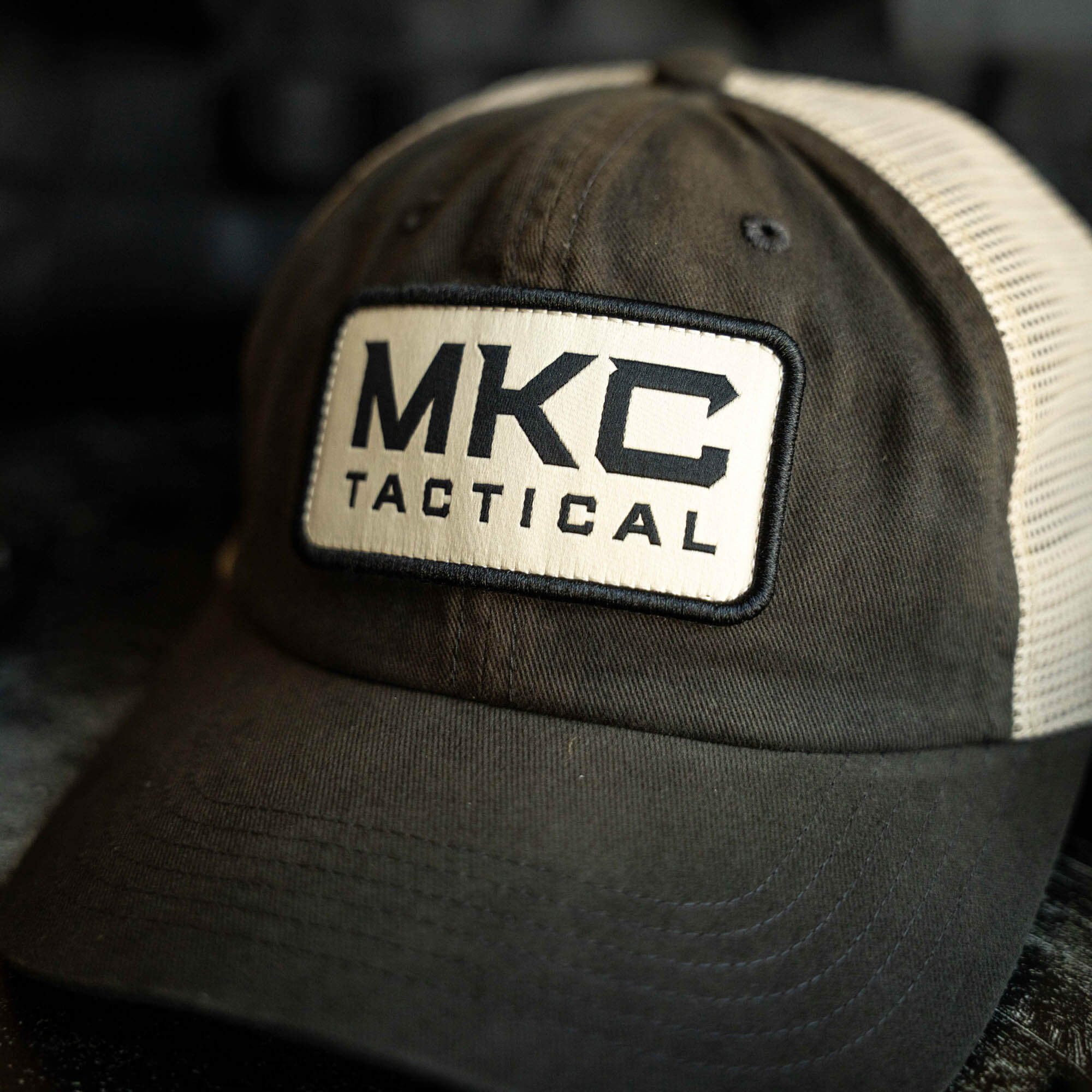 MKC Tactical Classic Trucker cap featuring a black front panel and beige mesh back, showcasing the MKC Tactical logo.