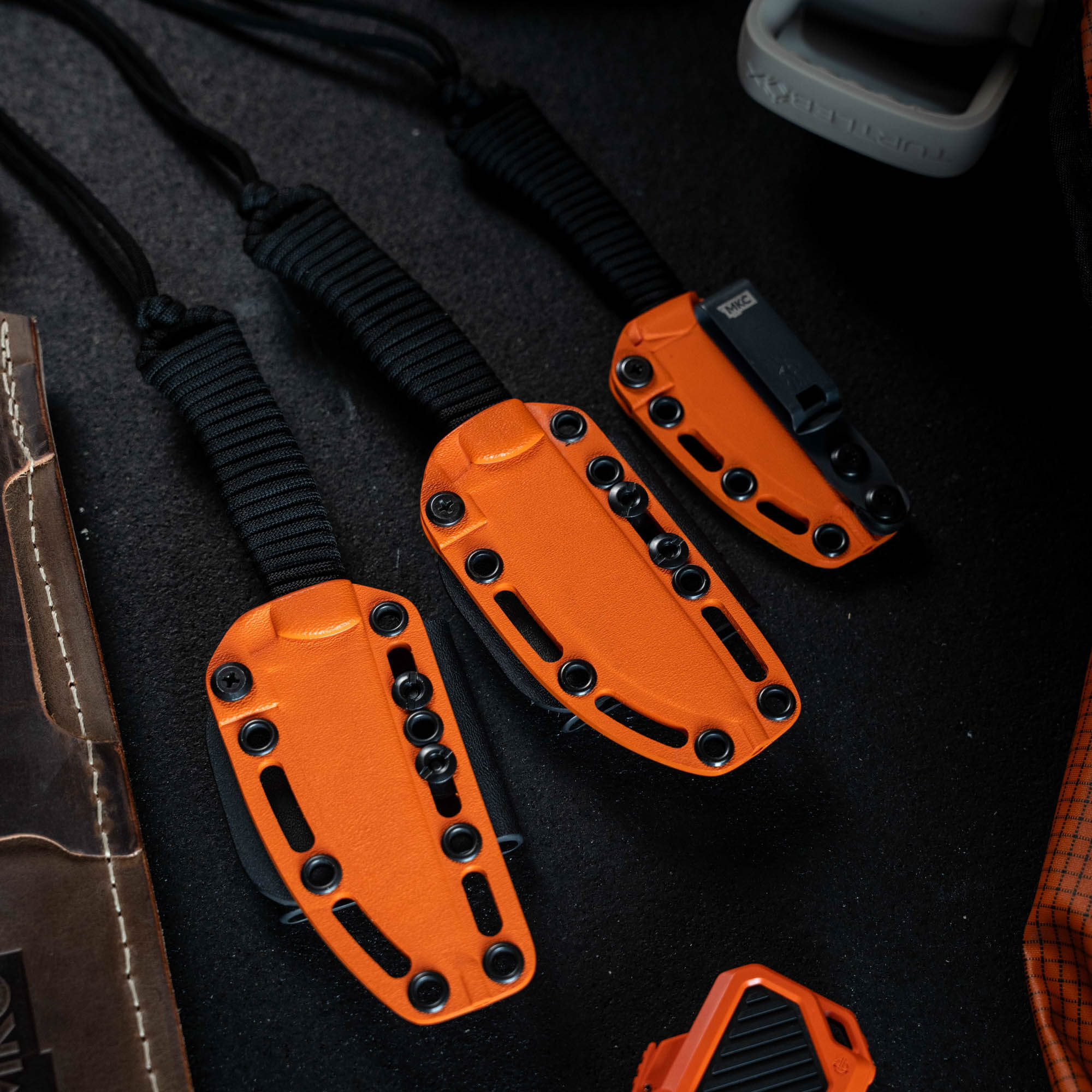 Full set of eight Blaze Orange Cerakote knives, featuring durable handles and tactical sheaths, ideal for outdoor use.