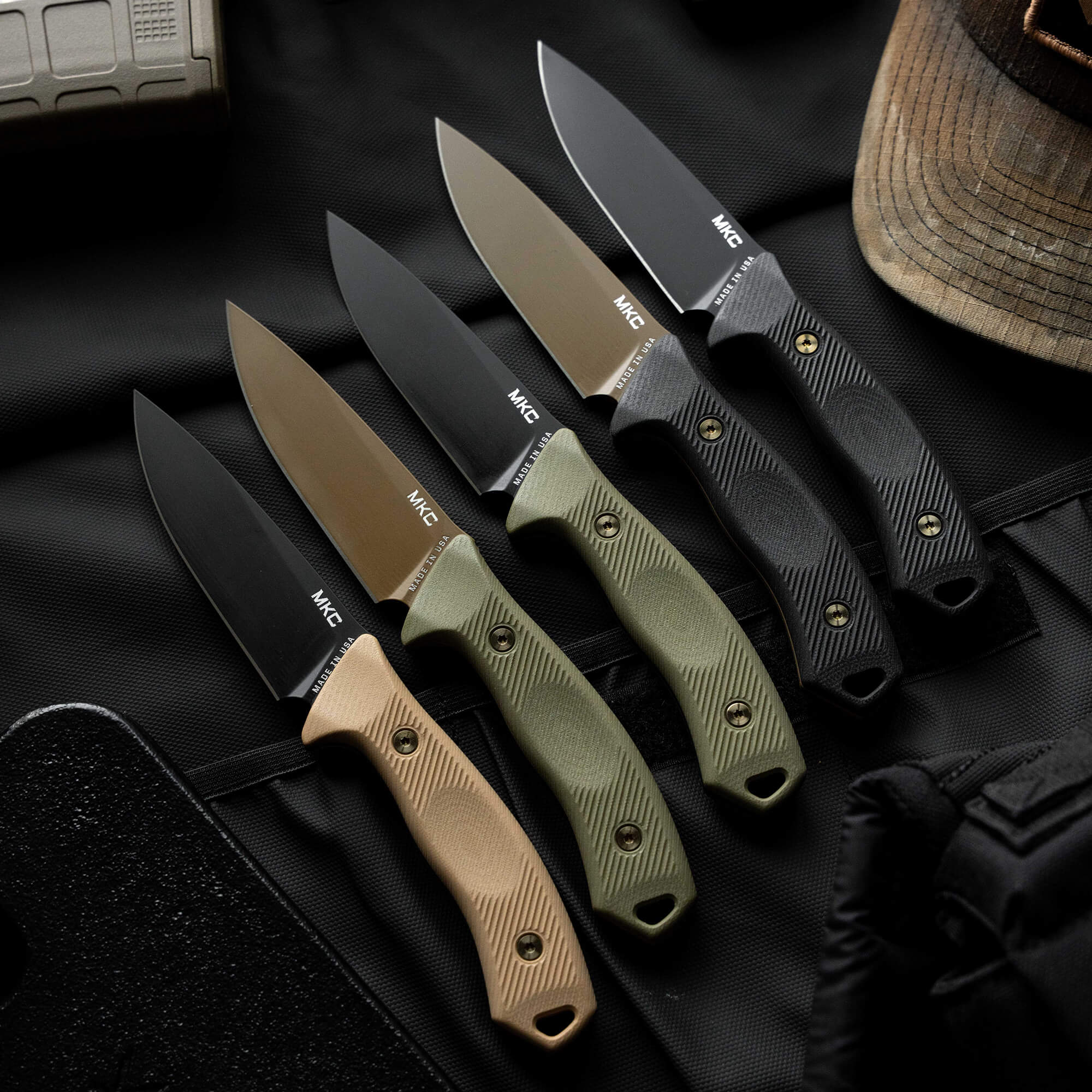 A collection of five MTNTOUGH TF24 knives featuring various blade finishes and handle colors, displayed on a dark background.