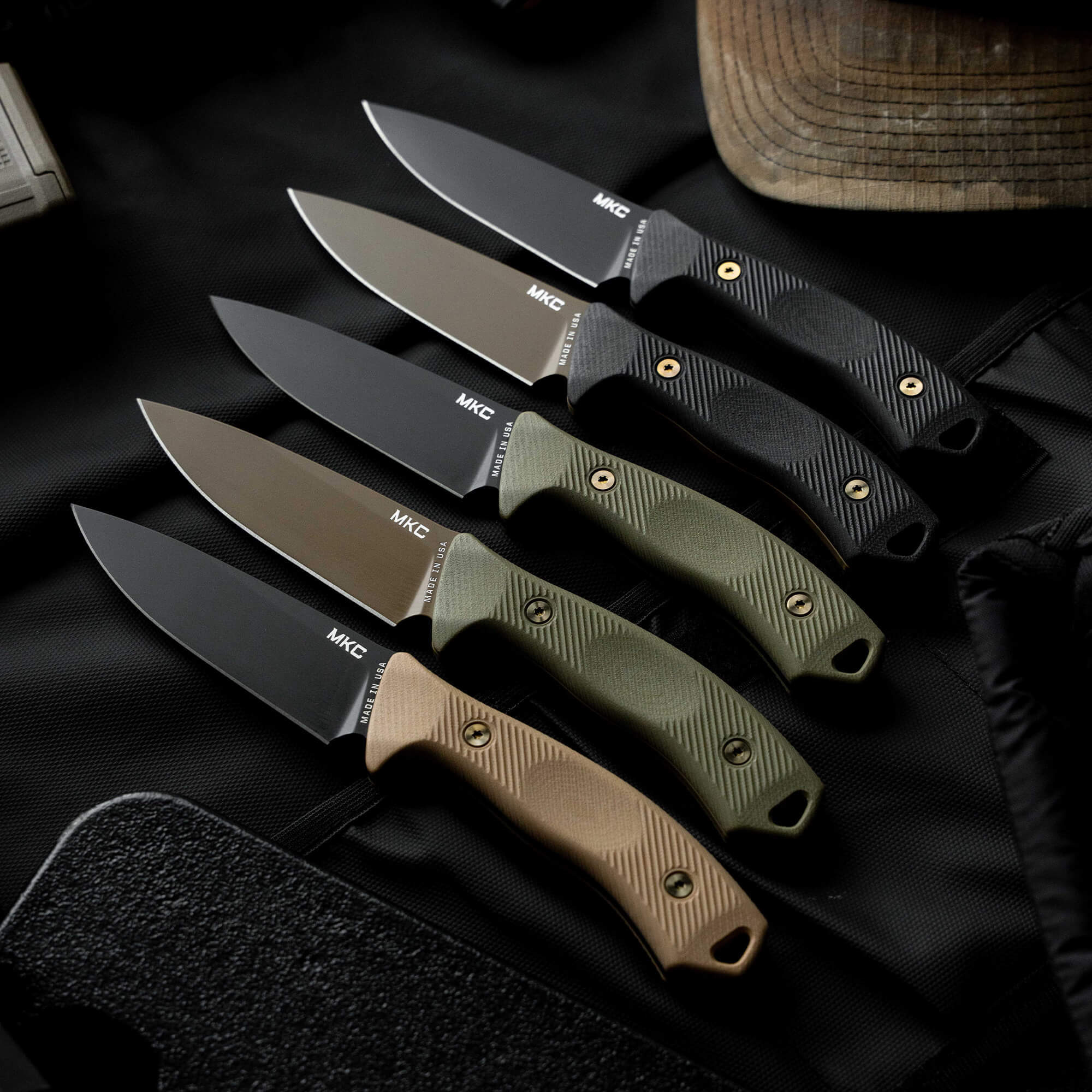 Montana Knife Company TF24 knives in various colors displayed on a textured surface, showcasing their rugged design and functionality.