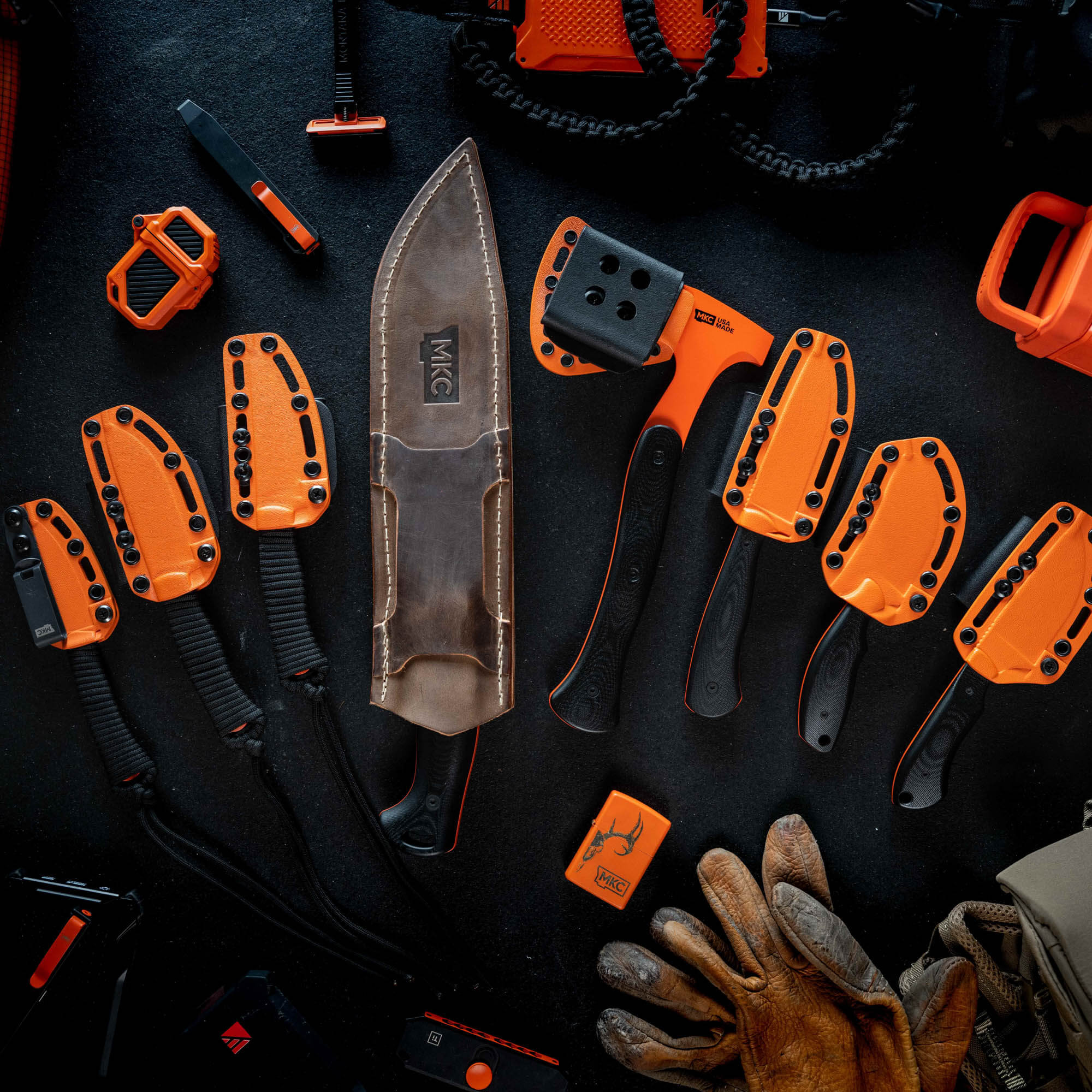 Full set of eight Blaze Orange Cerakote knives and tools arranged on a dark surface, showcasing durability and visibility.