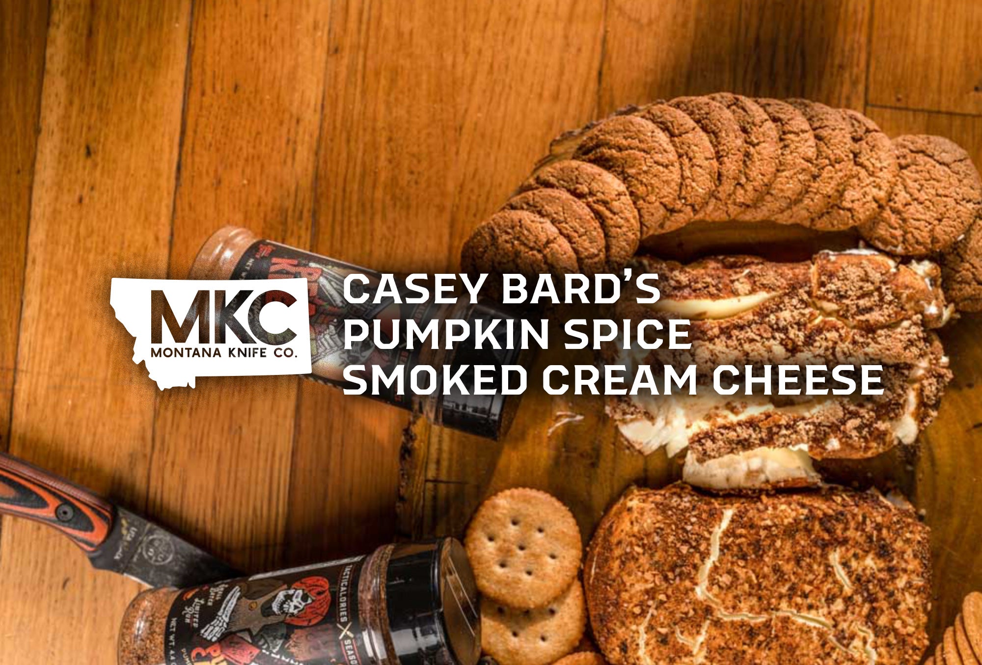 Two bricks of pumpkin spice smoked cream cheese sit on a wooden table next to ginger snaps, crackers, and spices.