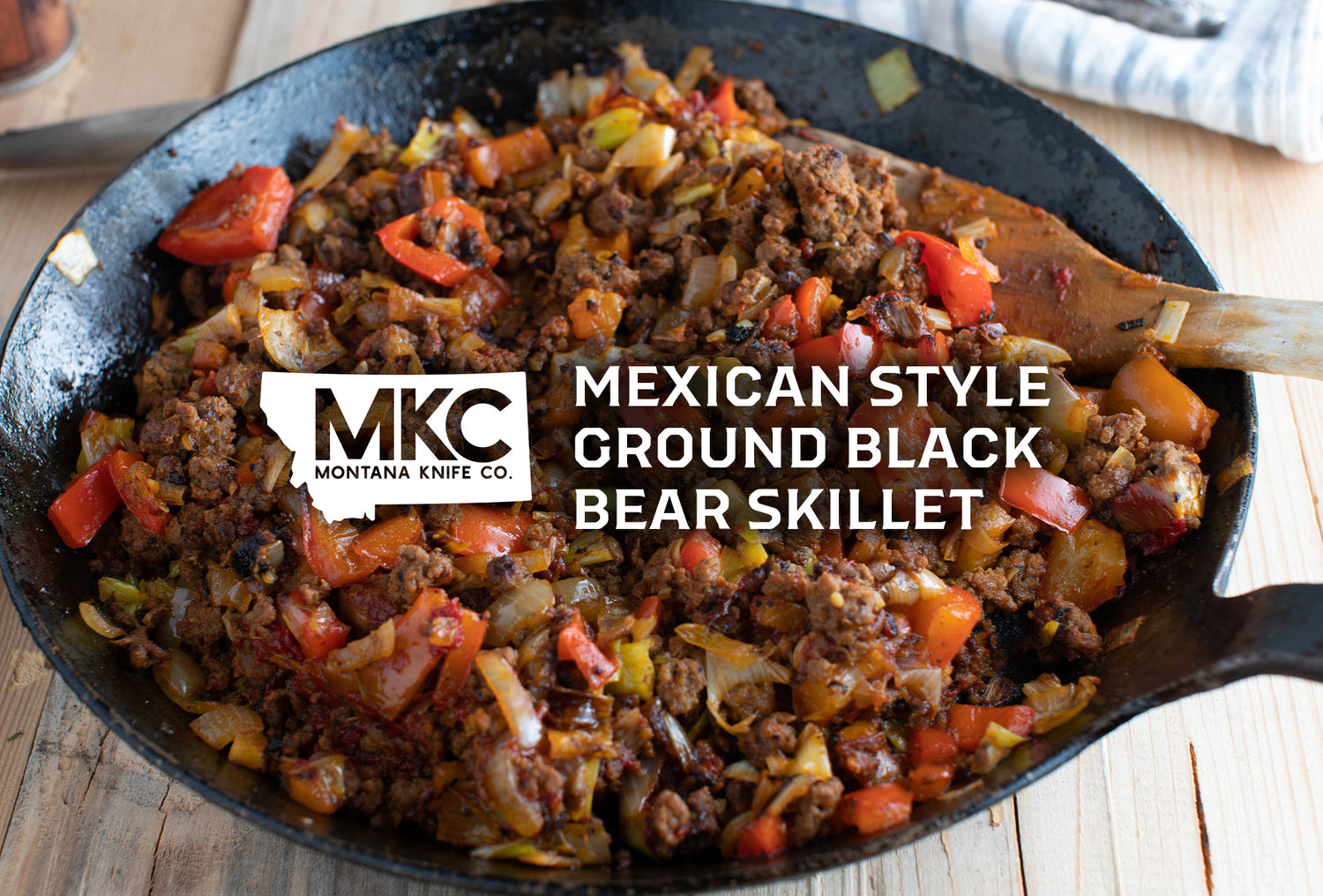 A wooden spoon stirs in a cast iron skillet, making a Mexican-inspired ground black bear meat recipe. 