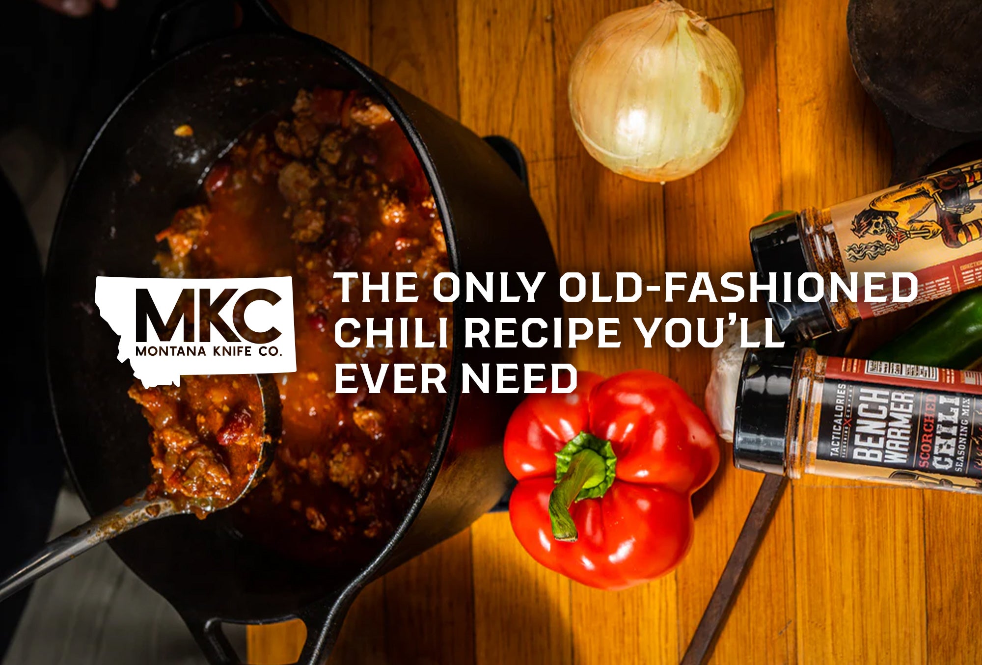 Cast-iron pot of old-fashioned chili with spoon, bell pepper, and onion.