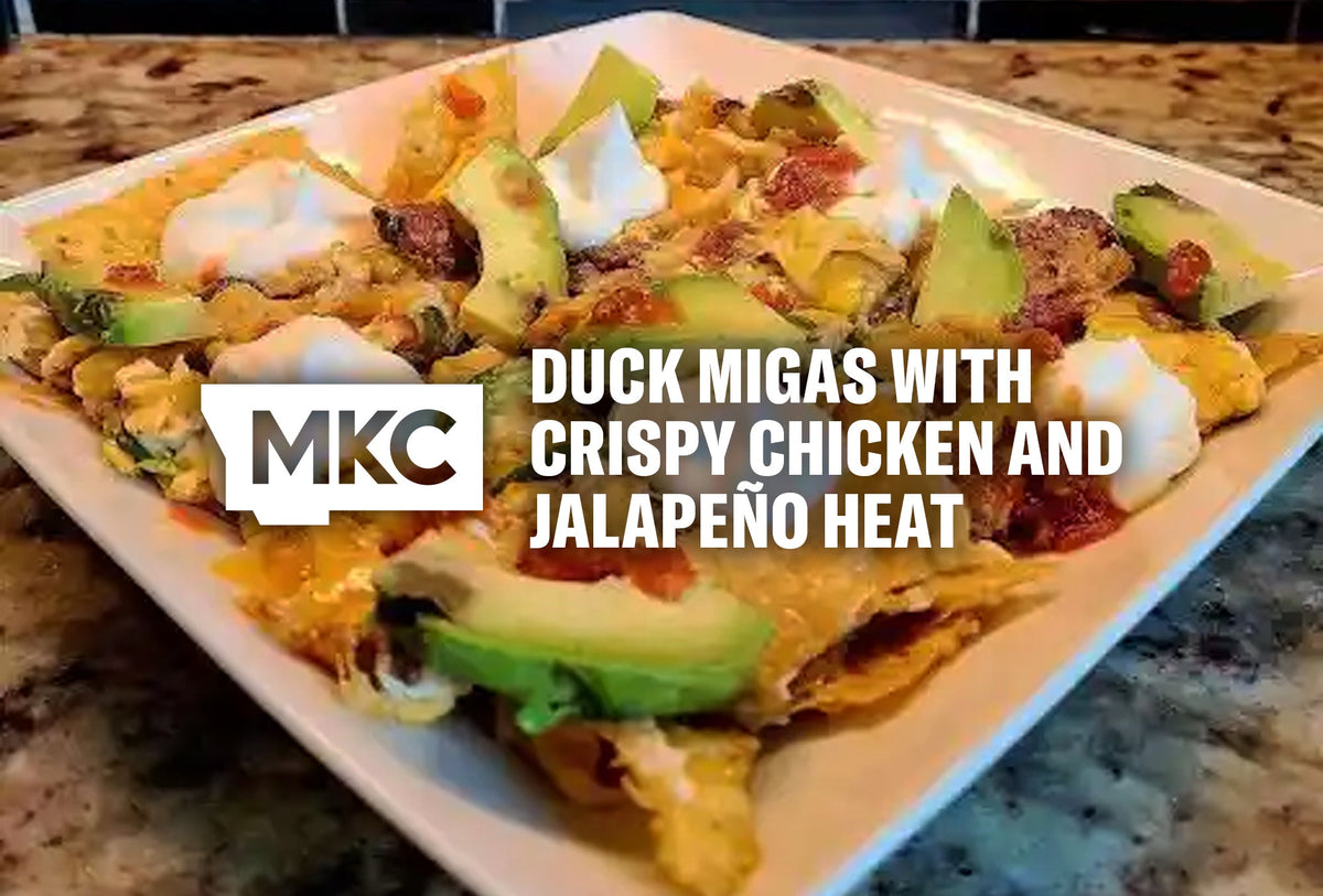Plate of duck migas topped with avocado, sour cream, salsa, and melted cheese over crispy tortilla chips.