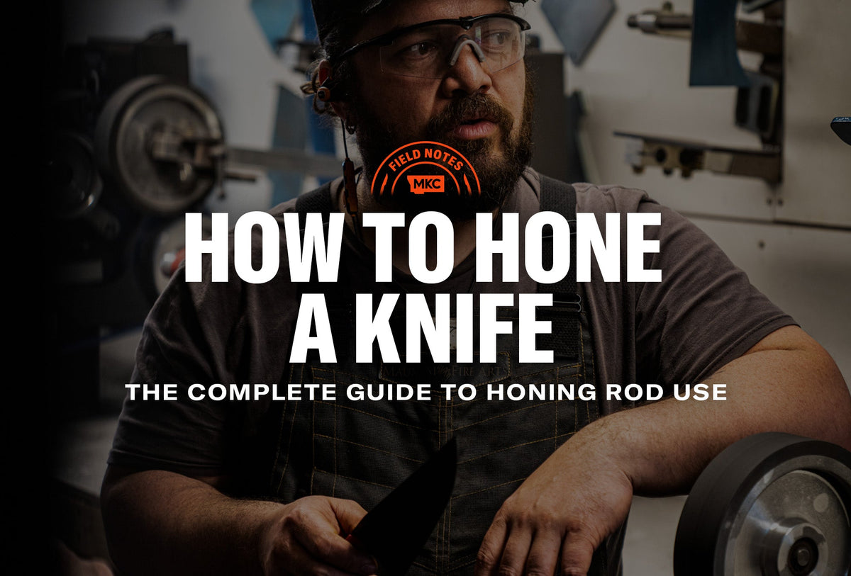 Person honing a knife with a honing rod in a workshop, wearing safety glasses and work attire.