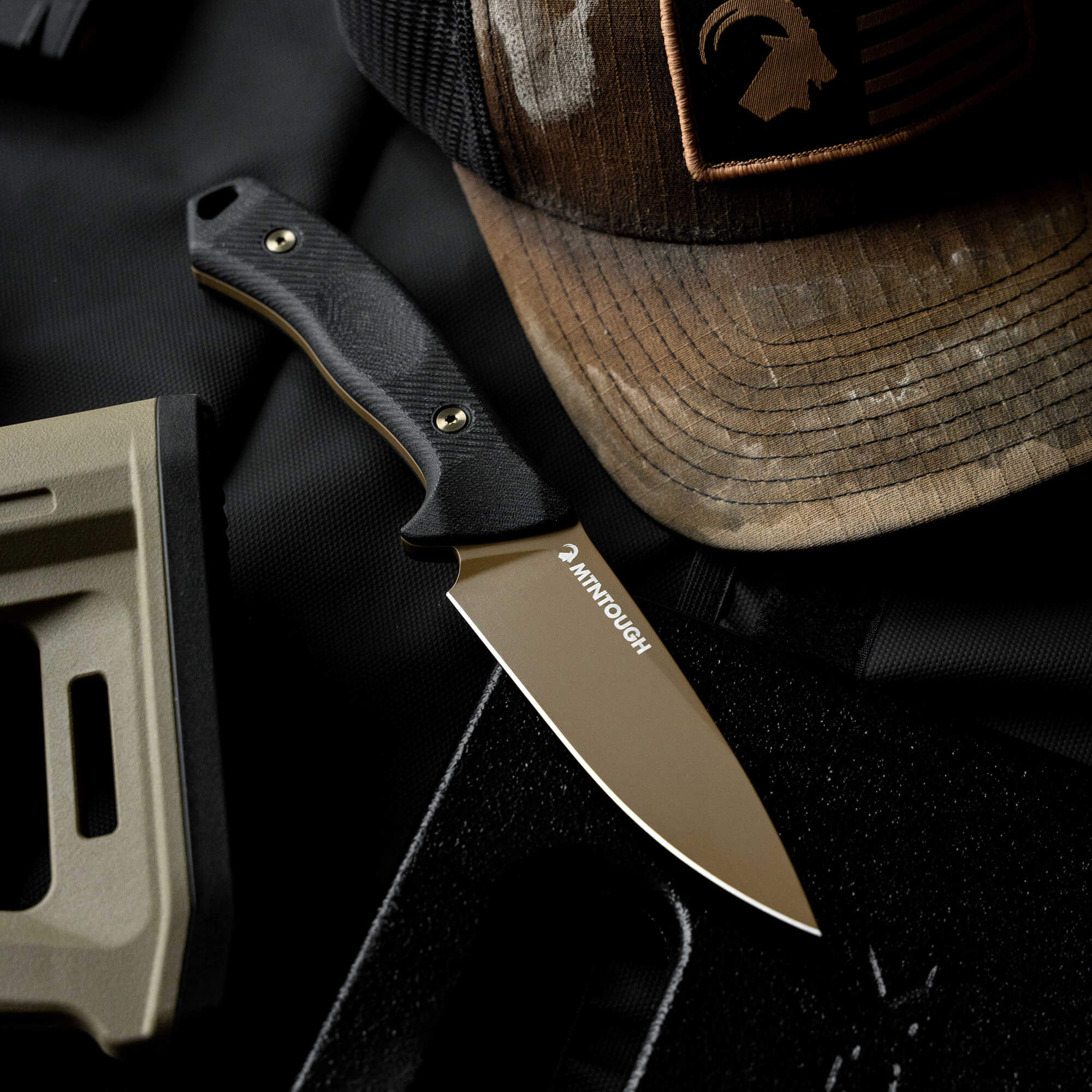 MTNTOUGH TF24 knife displayed on a tactical background with a worn cap, showcasing its durable design and craftsmanship.