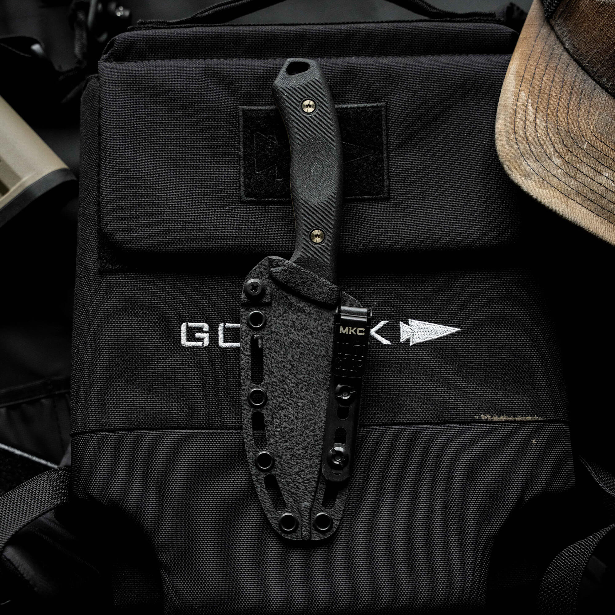 MTNTOUGH TF24 knife displayed on a tactical bag, featuring a sleek black blade and textured handle for grip.